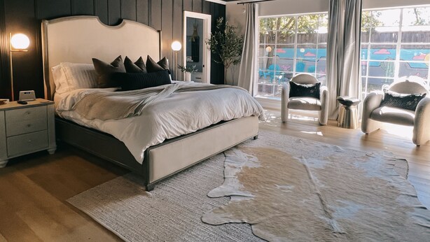 A modern bedroom with a large bed, bedside tables, a ceiling fan, and a view of the outdoors through large windows. - Spacious 6-bedroom house in marvelous Lubbock with AC, WiFi, fitness room (Lubbock)