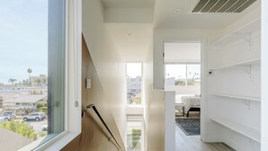 A modern, well-lit room with a large window, a staircase, and a view of the outside. - Stunning Hollywood Townhouse with Sunny views (Los Angeles)