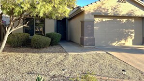 A residential house with a garage, a tree, and a well-maintained lawn.