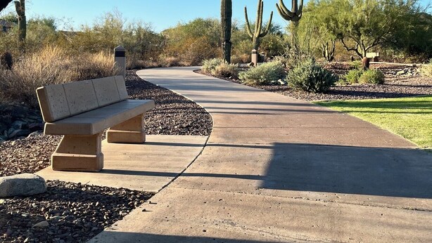 A park with a paved path, benches, and cacti.