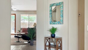 A spacious hallway with a tiled floor, a wooden console table with a plant, and a decorative mirror on the wall.