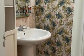 Ein Badezimmer mit einem weißen Waschbecken, einem Spiegel und einem Blumenmuster an der Tapete.