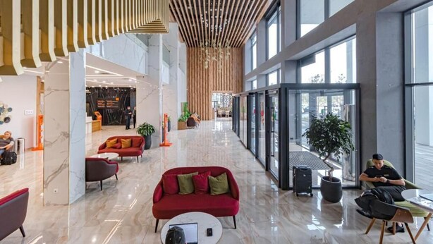 Een ruime lobby met een hoge plafond, moderne meubels en grote ramen.