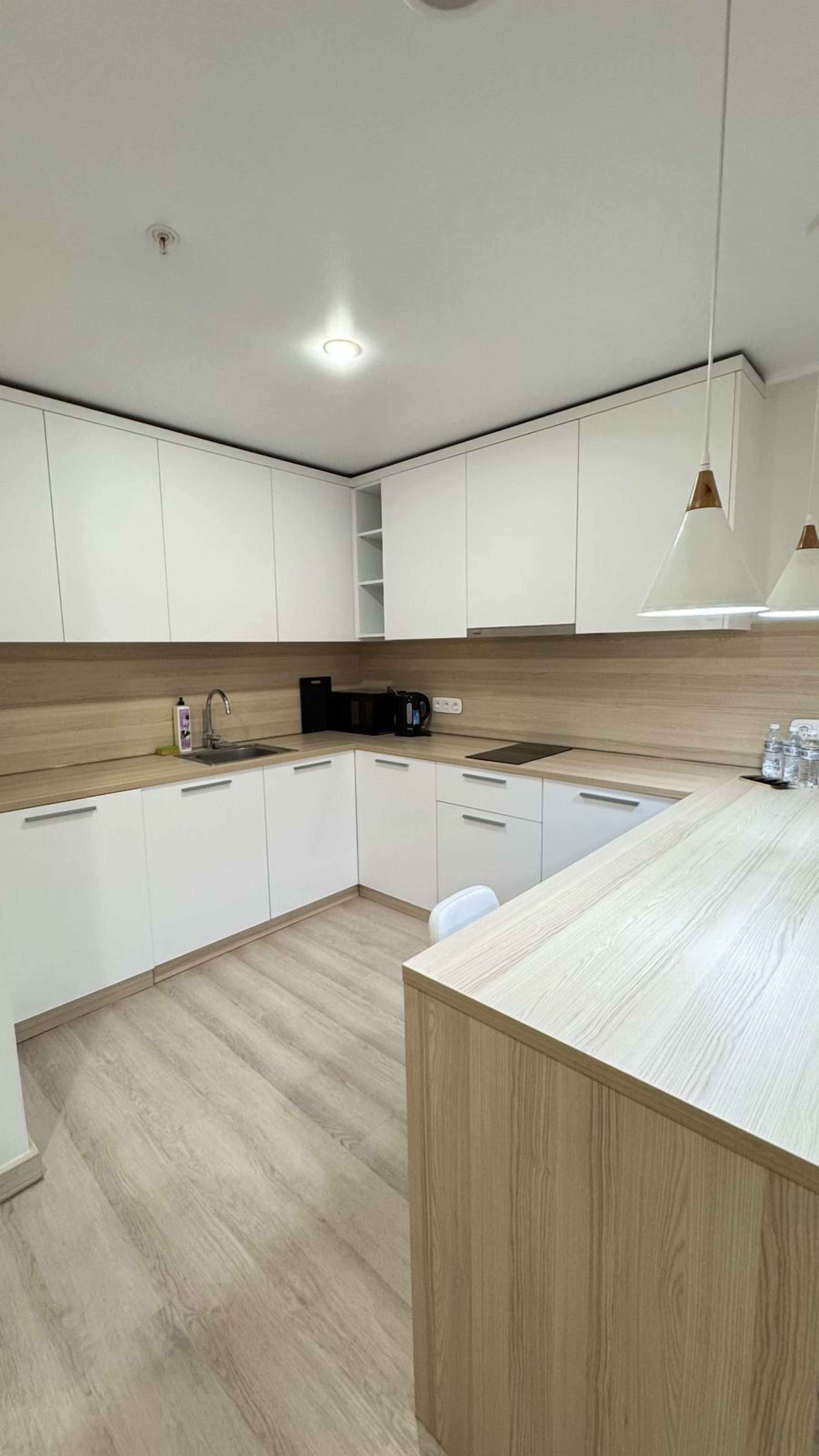 A modern kitchen with white cabinets, a wooden countertop, and a built-in island.