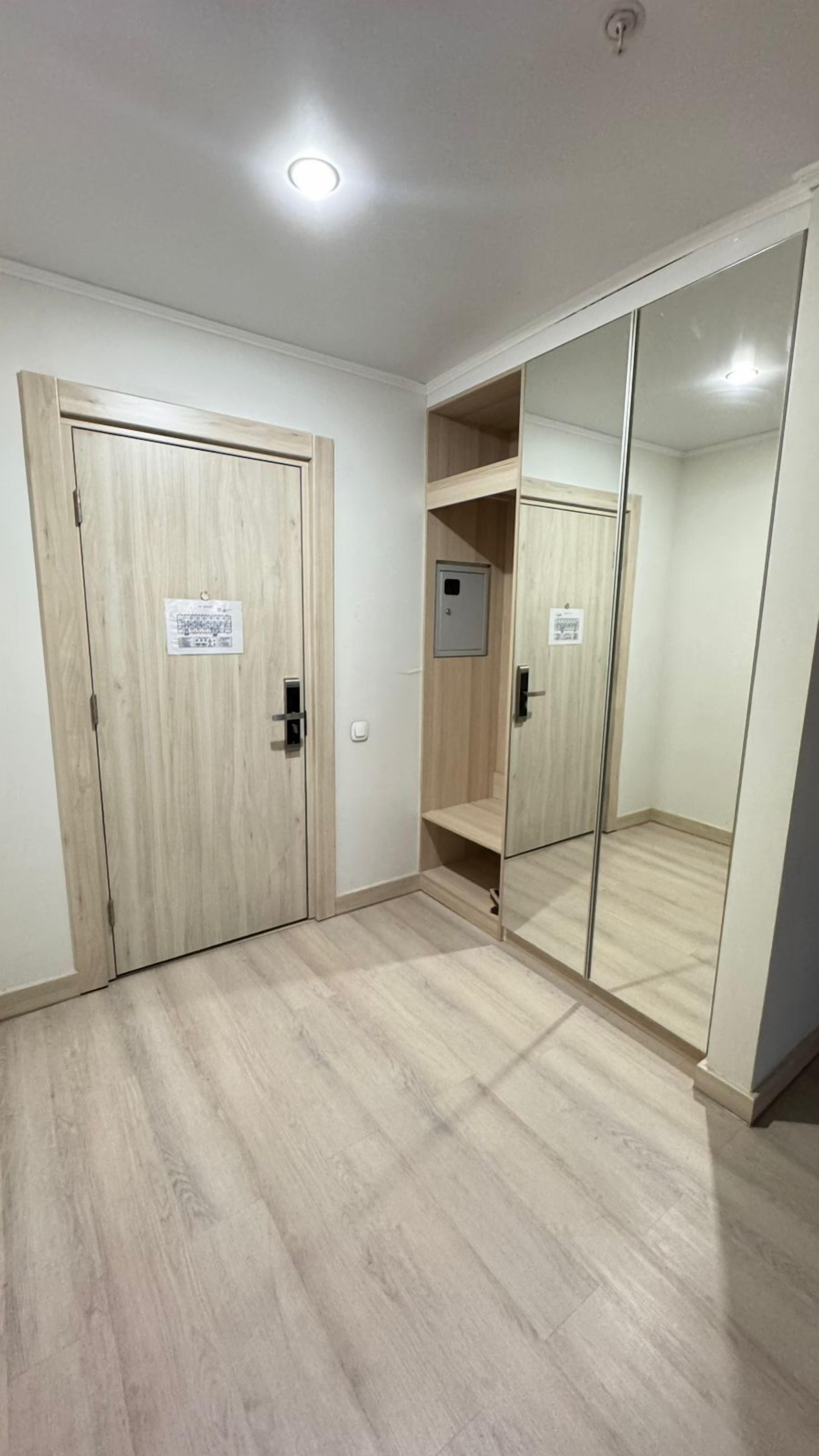 Une pièce dotée de deux portes en bois, d’un placard avec des portes miroir et d’un plancher en bois de couleur claire.