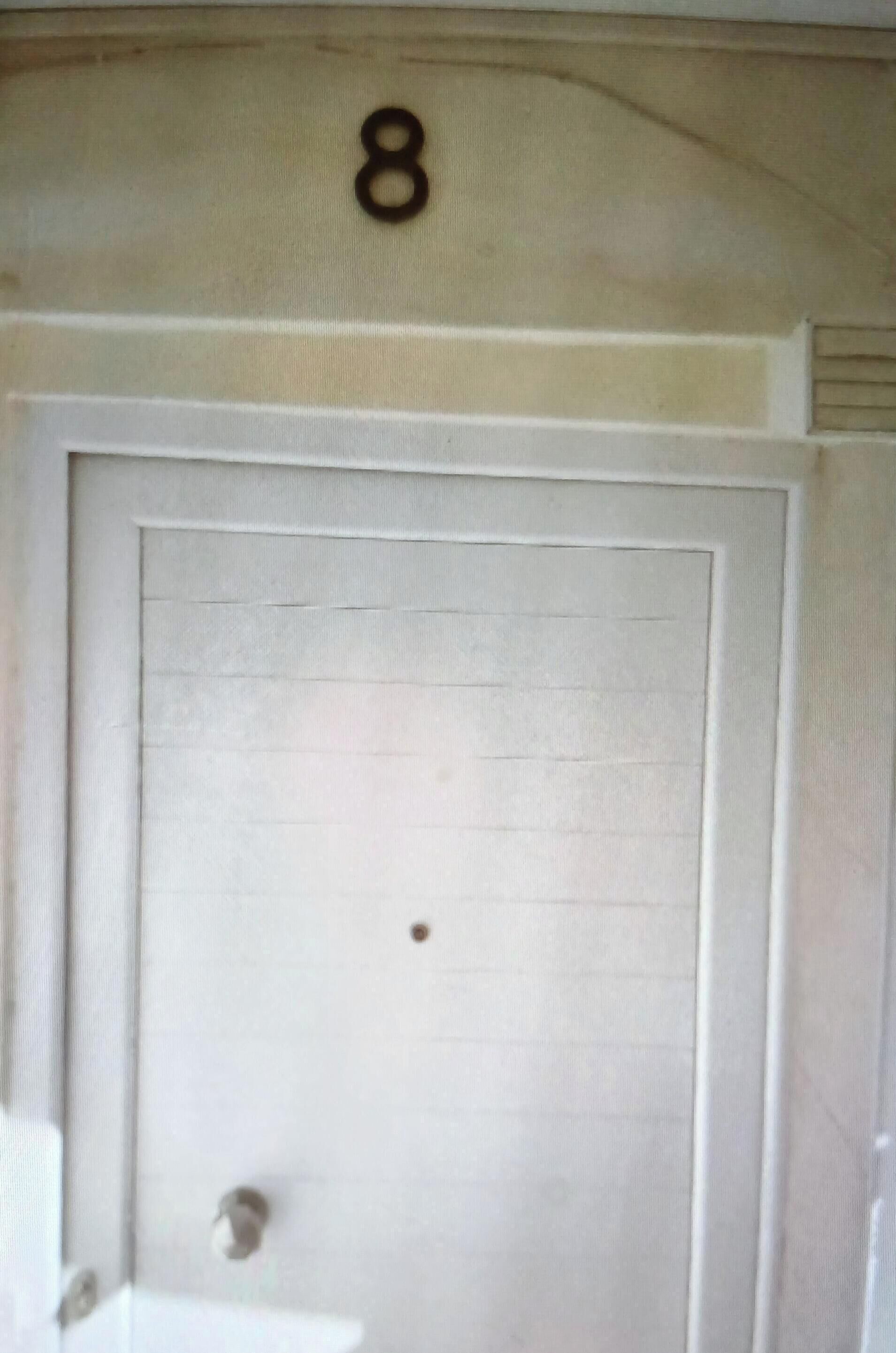 A white door with a number '8' above it, a small round doorknob, and a visible gap at the bottom.
