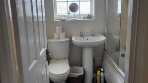 A compact bathroom with a toilet, sink, and a small window above the sink. - Cottage - Sleeps 4 - Garden - Parking (Chorley)