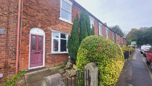 A brick house with a red door, a window, and a hedge. - Cottage - Sleeps 4 - Garden - Parking (Chorley)