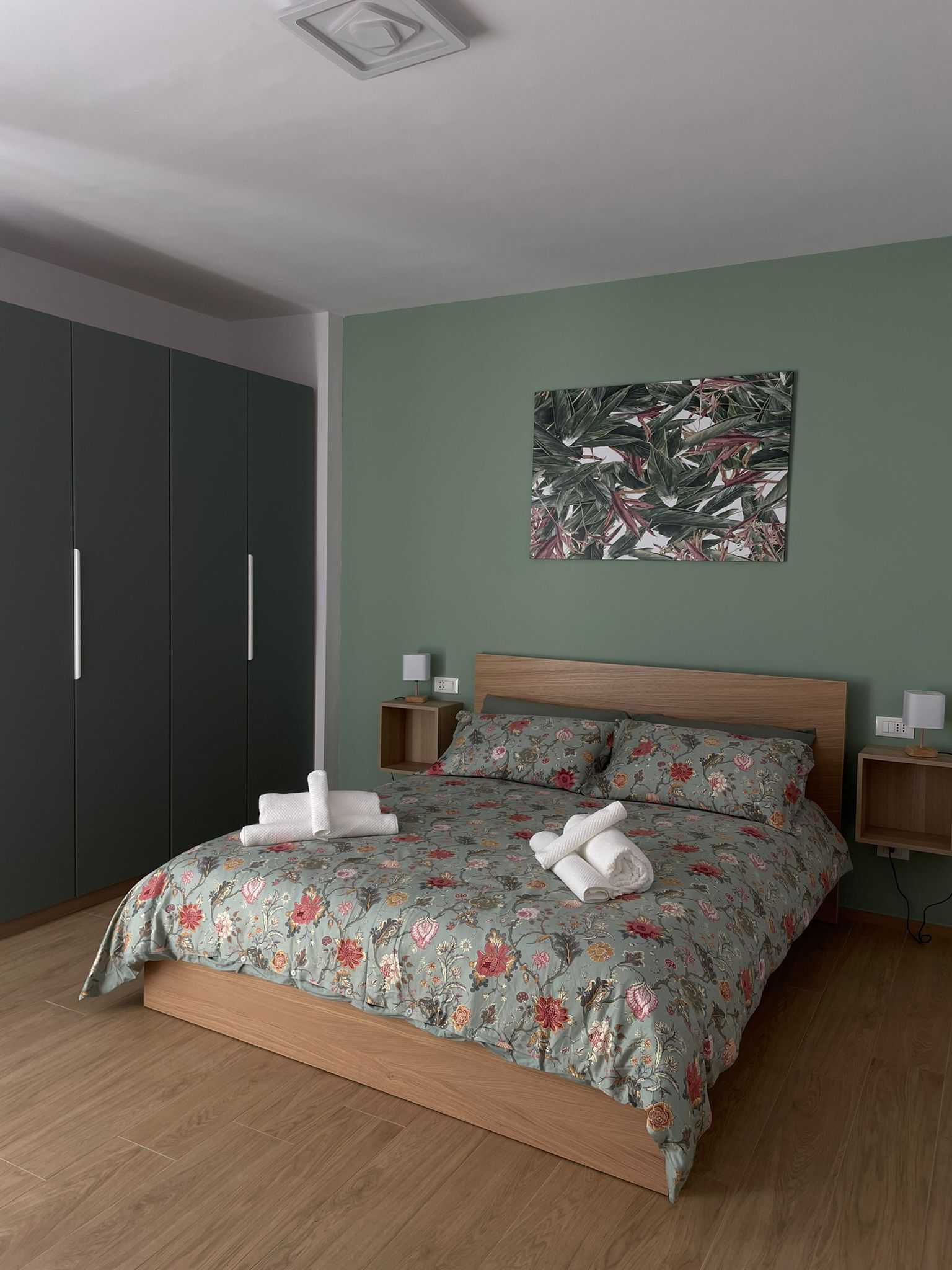 A bedroom with a bed, a nightstand, a wall-mounted lamp, and a wardrobe.