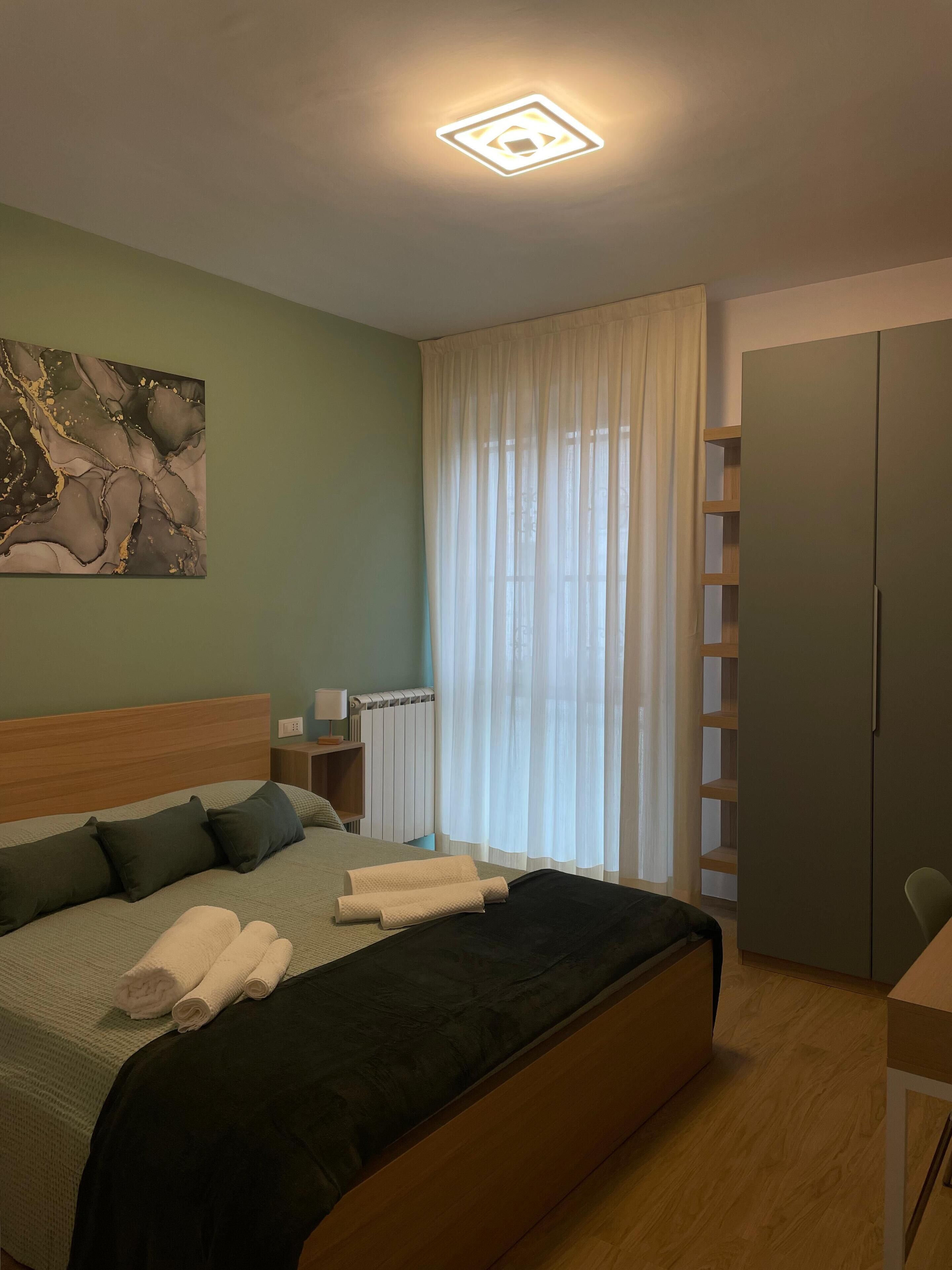 Une chambre bien rangée, avec un lit, une table de chevet, un radiateur et une armoire.