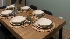 Een eethoek met een tafel voor vier personen, een aan de muur bevestigde televisie en een schilderij van toekans.
