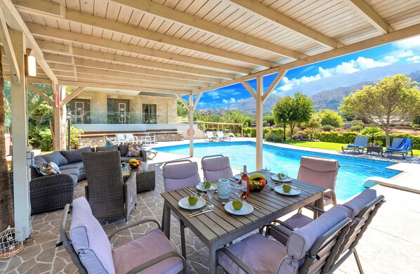 An outdoor patio with a pool, dining area, and seating.