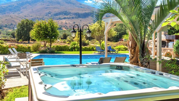 A hot tub with a pool and lounge chairs, surrounded by greenery and a mountain view. - Mirsini Villa Private Pool & Jacuzzi (Georgioupoli)