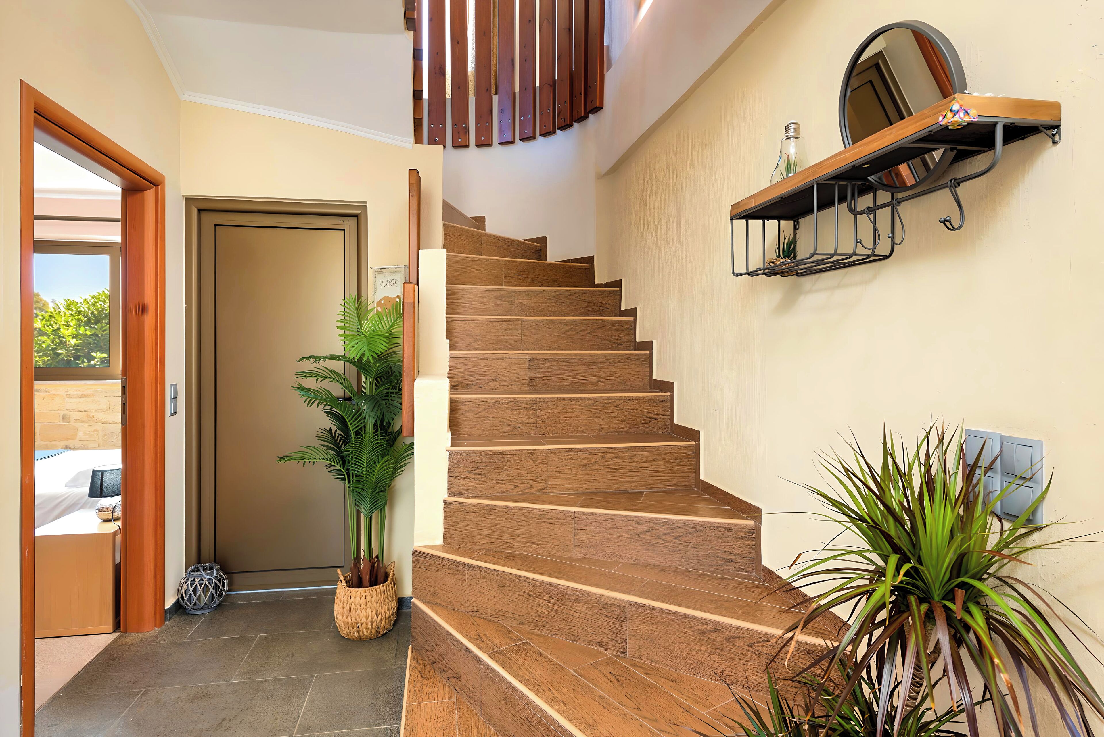 A wooden staircase with a handrail, a potted plant, and a wall-mounted shelf with a mirror.