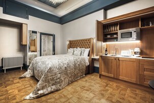 A bedroom with a bed, wooden wardrobe, and a built-in microwave.