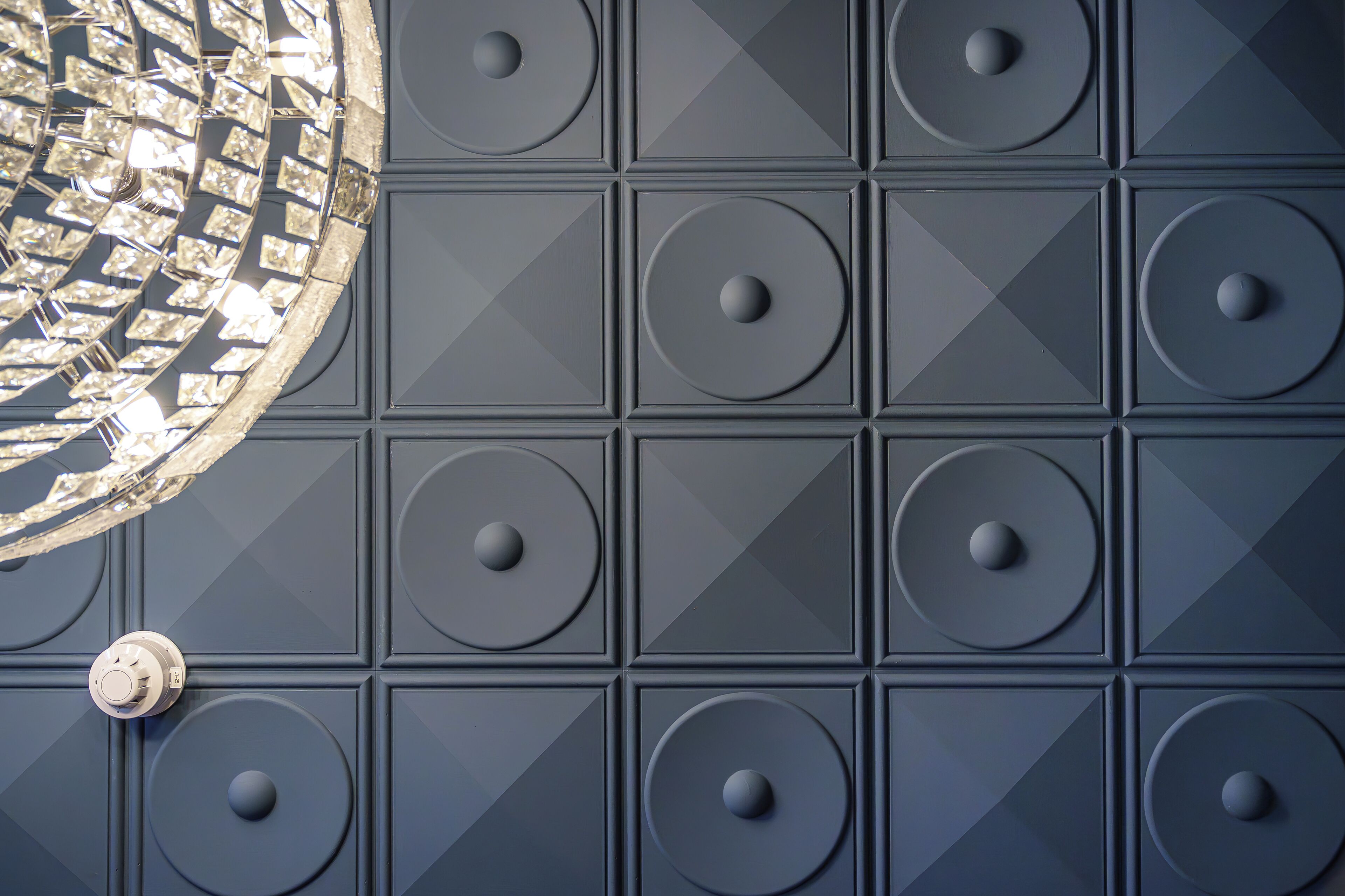 A close-up of a wall with a geometric pattern of recessed panels and circular indentations.