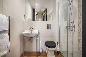 A modern bathroom with a glass shower enclosure, a white sink, and a black toilet.