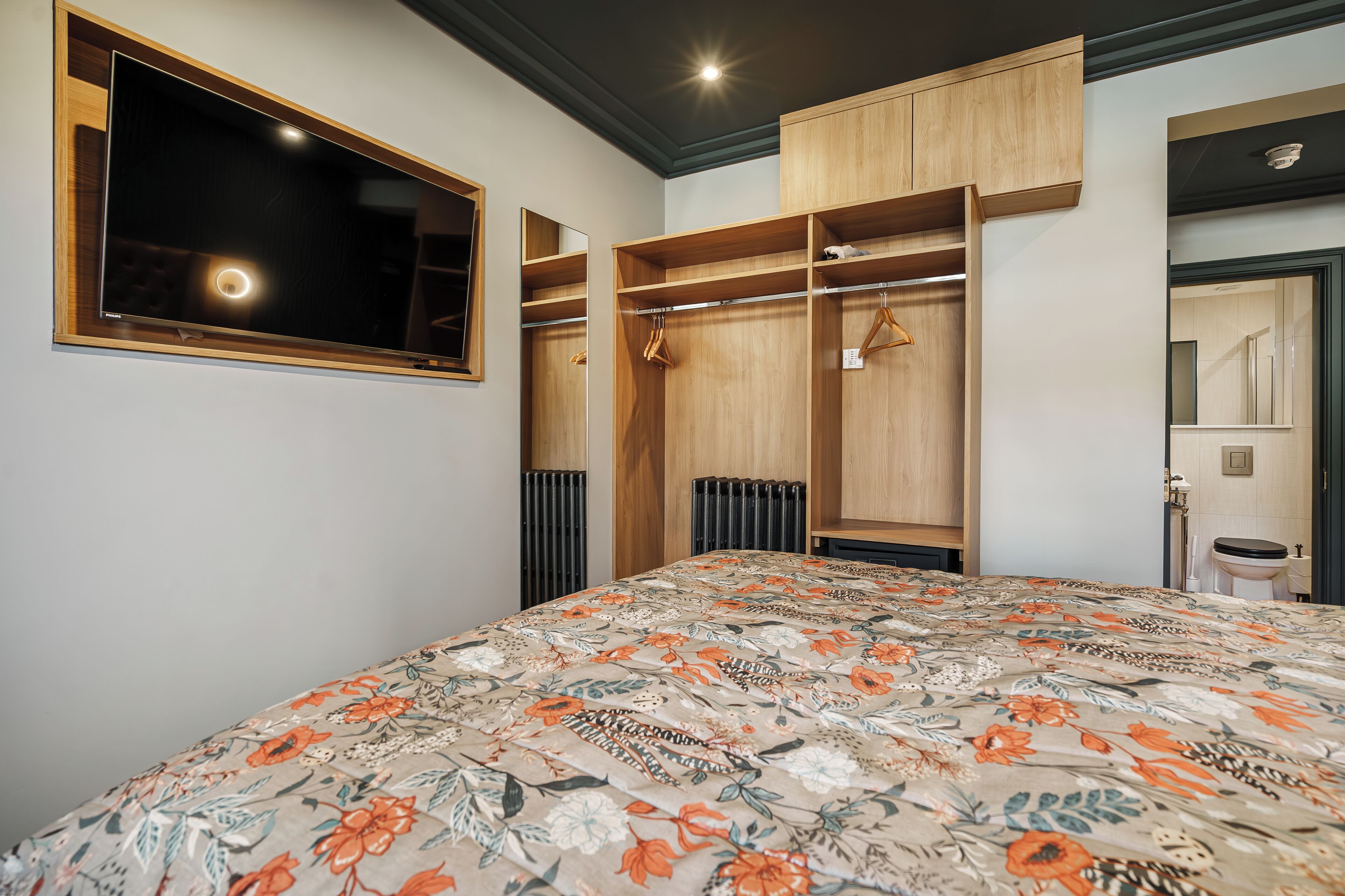 A bedroom with a bed, a wardrobe, and a mirror.