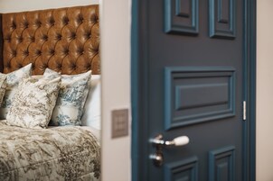 A bedroom with a tufted headboard, patterned bedding, and a blue door.
