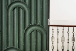 A close-up of a green textured wall with vertical lines and a metal railing with ornate patterns.