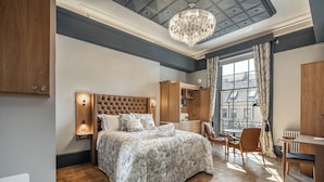 A bedroom with a tufted headboard, a large bed, a desk, and a chair. - Bonnie Hotel - Smart Boutique ApartHotel - Haymarket Edinburgh (Edinburgh)