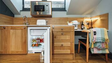 Una cocina compacta con armarios de madera, microondas integrado, tostadora y refrigerador.