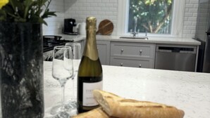A kitchen with a marble countertop, a bottle of wine, two glasses, and a bouquet of flowers.