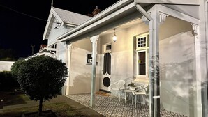 A house with a covered porch, a small garden, and a white fence.
