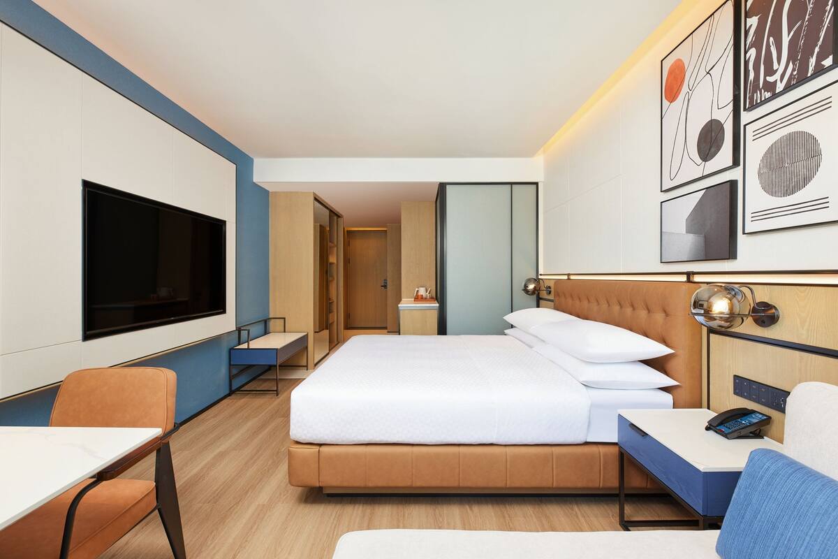 Una habitación de hotel moderna con una cama grande, un escritorio y una televisión.