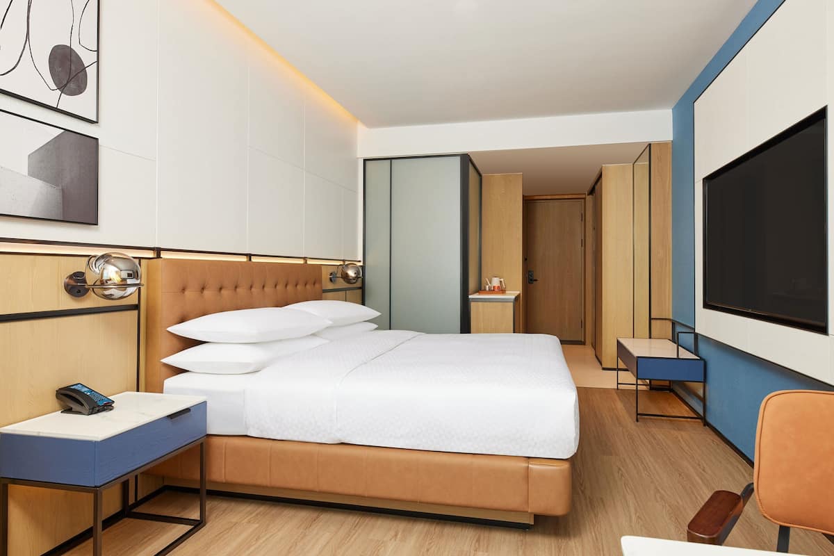Una habitación de hotel moderna con una cama grande, una mesita de noche y un televisor.
