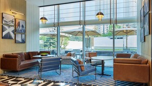 A modern lounge area with leather sofas, a coffee table, and a patterned rug. Large windows offer a view of the outdoors. - Four Points By Sheraton Chongqing North Railway Station (Chongqing)