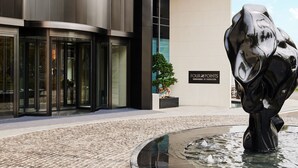 A modern building facade with a glass entrance, a black sculpture, and a sign reading "FOUR POINTS." - Four Points By Sheraton Chongqing North Railway Station (Chongqing)