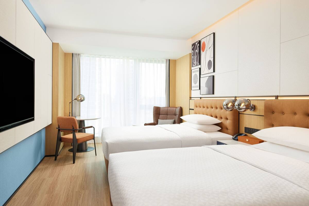 Habitación de hotel con dos camas, televisión, silla y mesa.