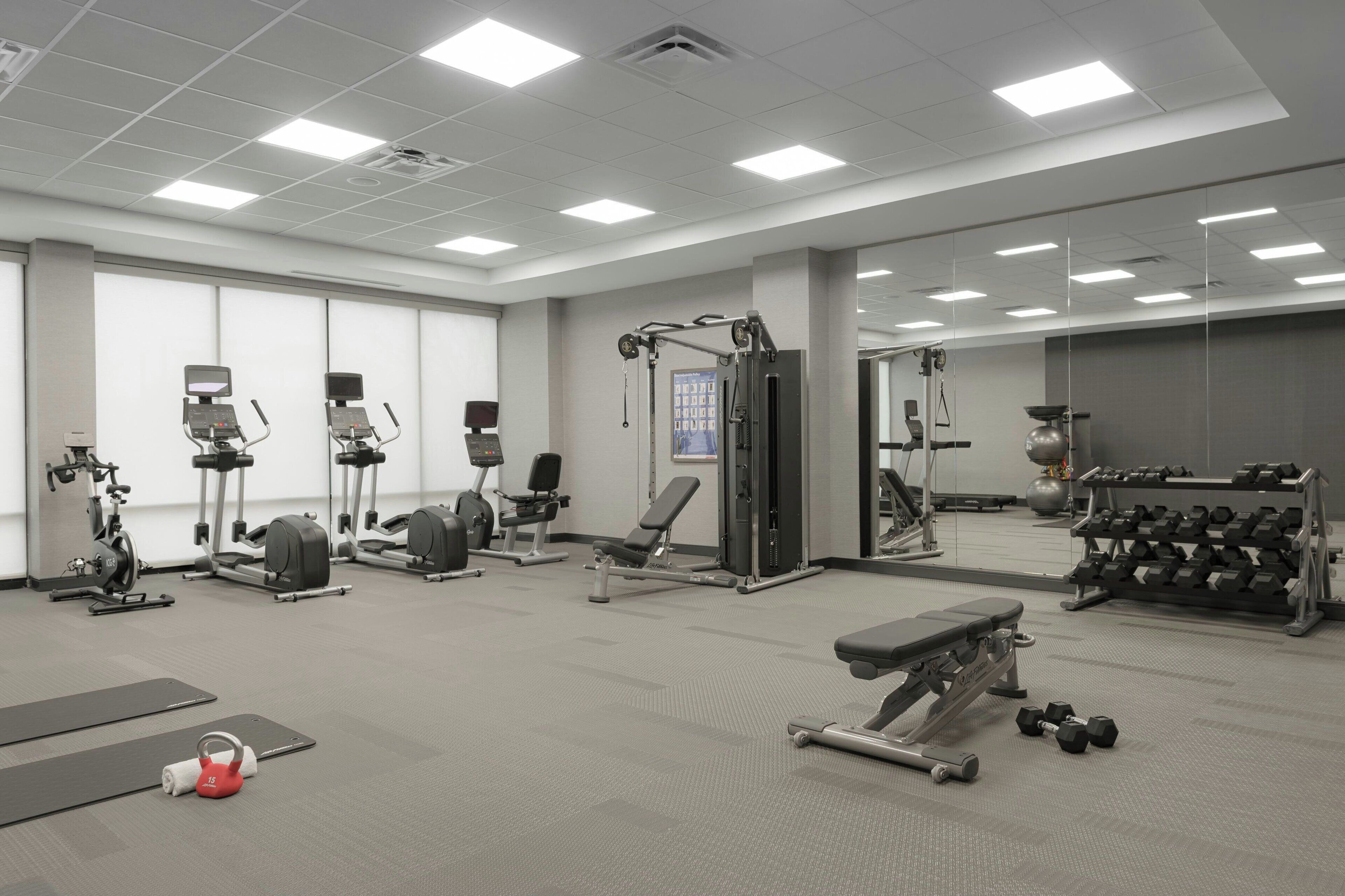 A gym with various exercise equipment, including treadmills, stationary bikes, and weight machines.