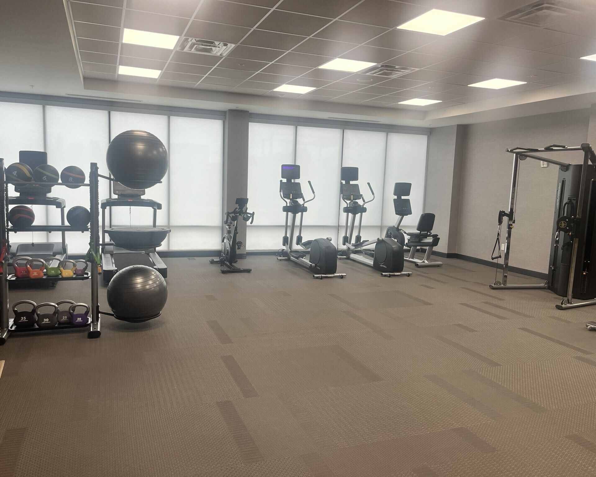 Een sportschool met diverse fitnessapparaten, waaronder loopbanden, elliptische trainers en gewichten.