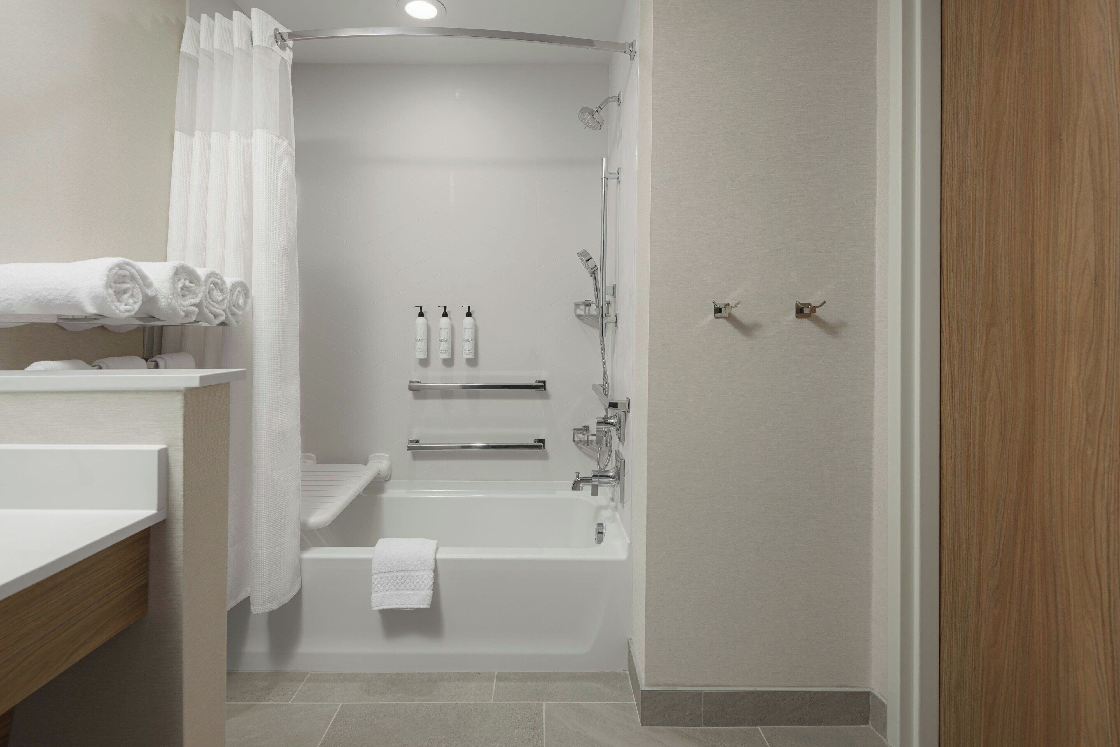 A modern bathroom with a bathtub, shower, and a vanity with a towel rack.