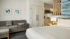 Een hotelkamer met een bed, een bank, een kleine tafel, een bureau, een magnetron en een kitchenette.