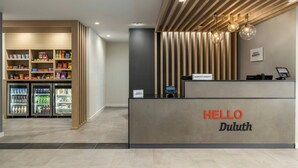 Een receptiegedeelte met een 'HELLO Duluth' bord, een zelfbedieningskiosk en gekoelde drankautomaten.