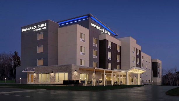 Een modern hotel met 'Towneplace Suites by Marriott' aanduiding, een overdekt buitenzitgedeelte en een goed verlichte ingang.