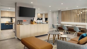 Een moderne woonruimte met een keuken, een flatscreen-tv en een zithoek met tafels en stoelen.