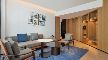 A modern living room with a sofa, armchairs, a coffee table, and a wall-mounted TV.