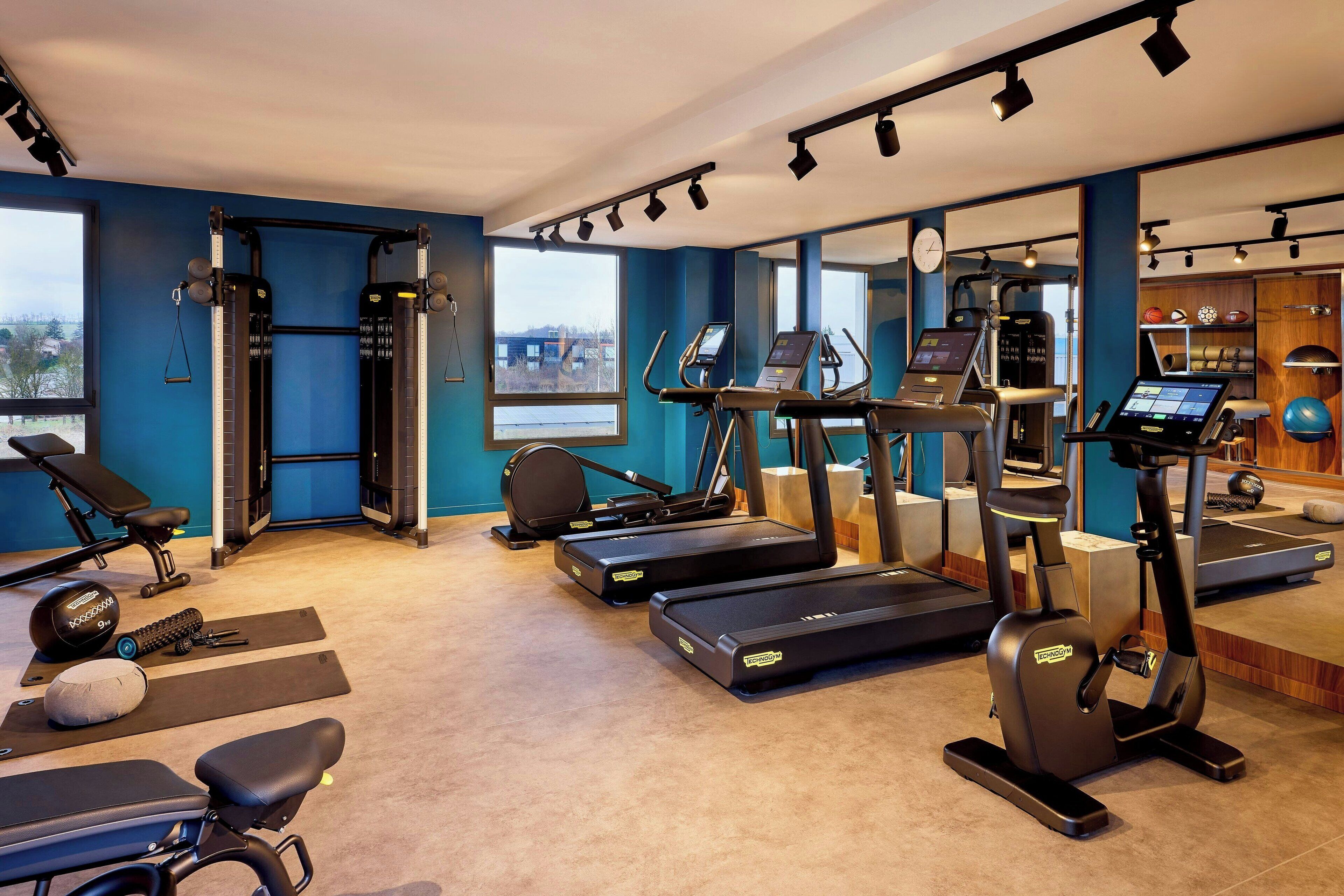 Een sportschool met loopbanden, elliptische trainers en krachttrainingapparatuur.