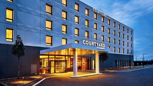 Ett Courtyard by Marriott-hotell med en modern fasad, stora fönster och en väl upplyst entré.