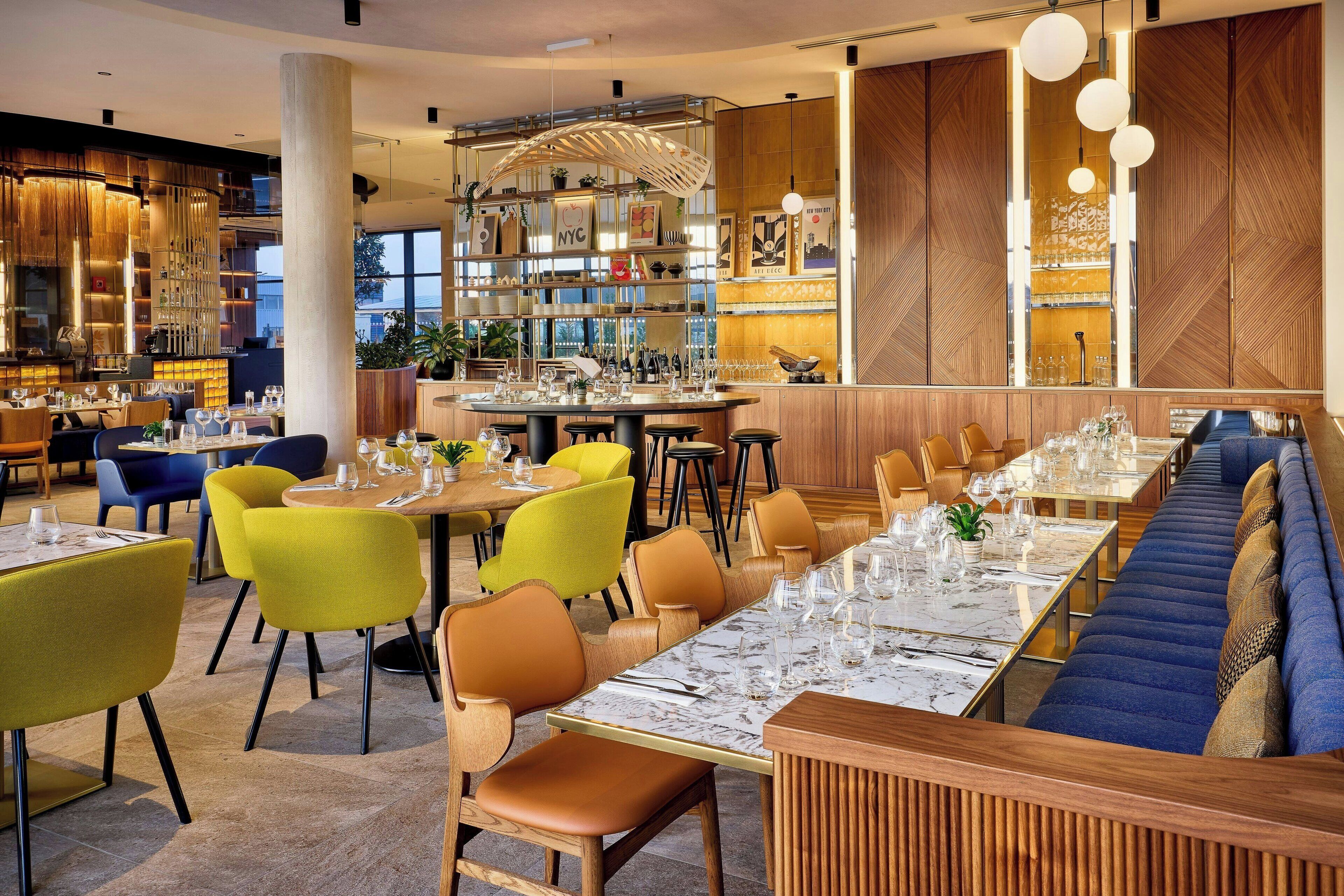 Um restaurante moderno com uma mesa comunitária grande, cabines individuais e um bar.