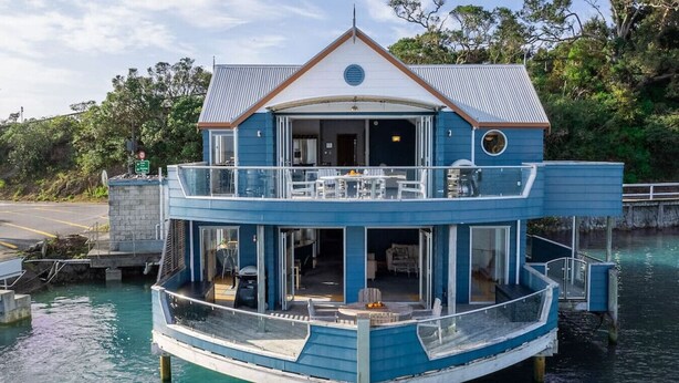 A two-story boat with a balcony and a covered outdoor seating area.
