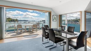 Ein moderner Essbereich mit Blick auf den Hafen, der einen Tisch mit Stühlen, ein großes Fenster sowie eine Aussicht auf Boote und Wasser zeigt.