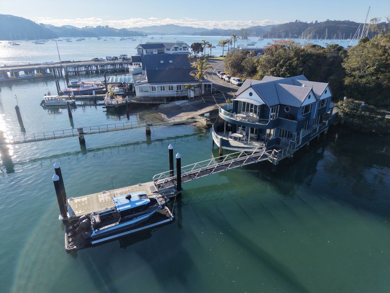 A waterfront property with a dock, a large house with a balcony, and a view of the water.