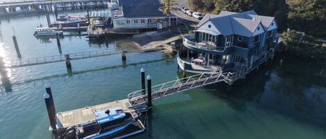 A waterfront property with a dock, a large house with a balcony, and a view of the water.