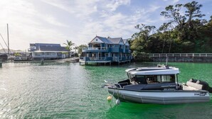 Ein Wohnhaus direkt am Wasser mit einem großen, blauen Haus und einem kleineren Gebäude, beide auf Stelzen über dem Wasser errichtet.