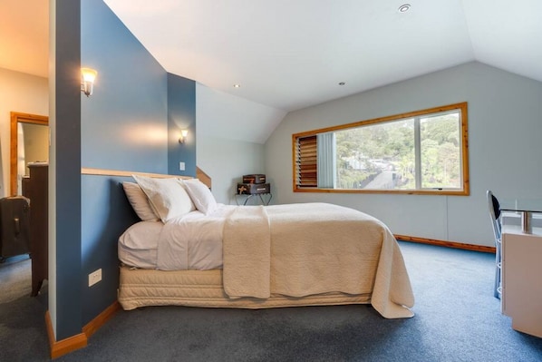 Une chambre à coucher comprenant un lit, un bureau, une chaise, une fenêtre et une vue sur l’extérieur.